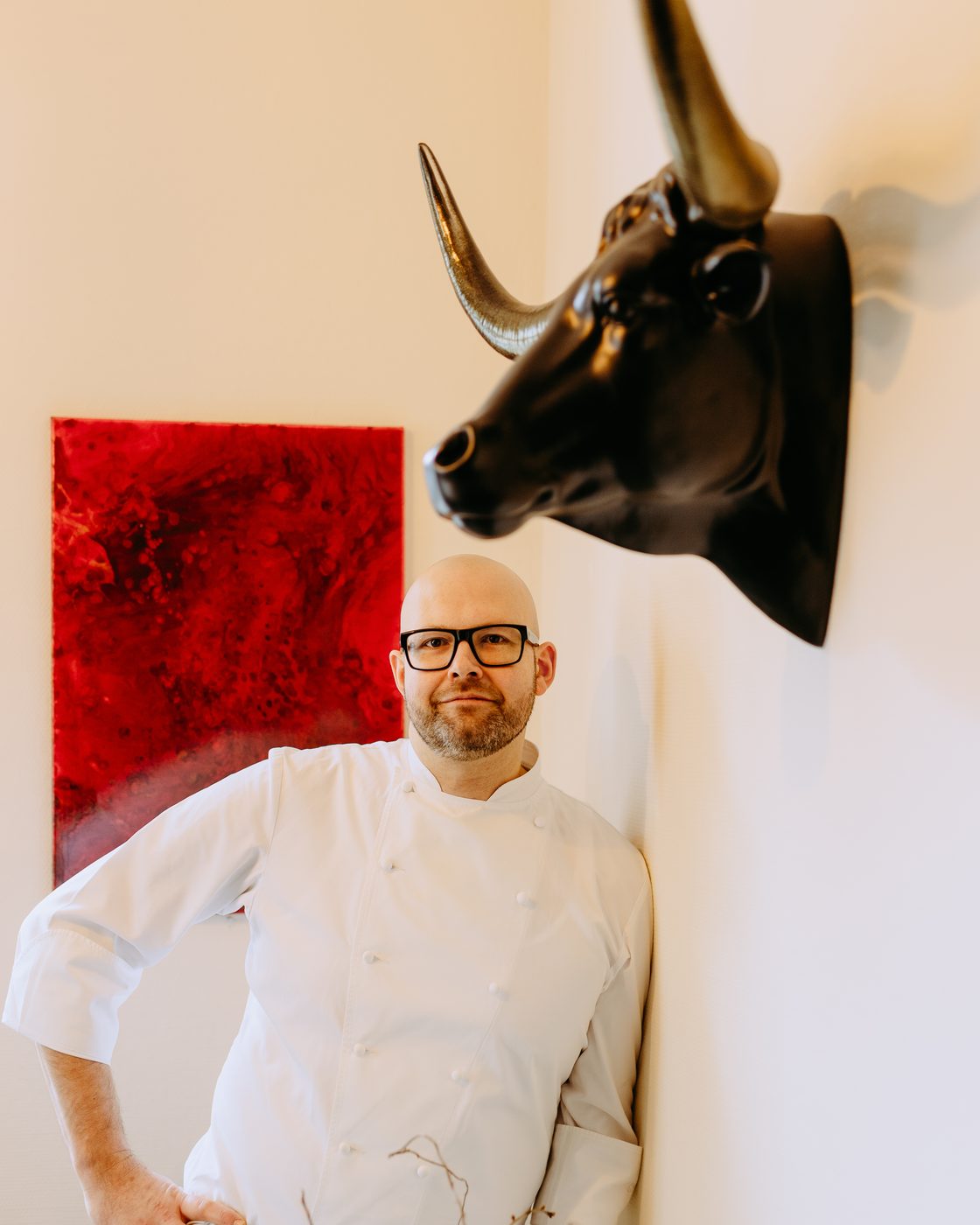 Küchenchef Jens Franke in weißer Kochjacke an einer Wand im Gastraum